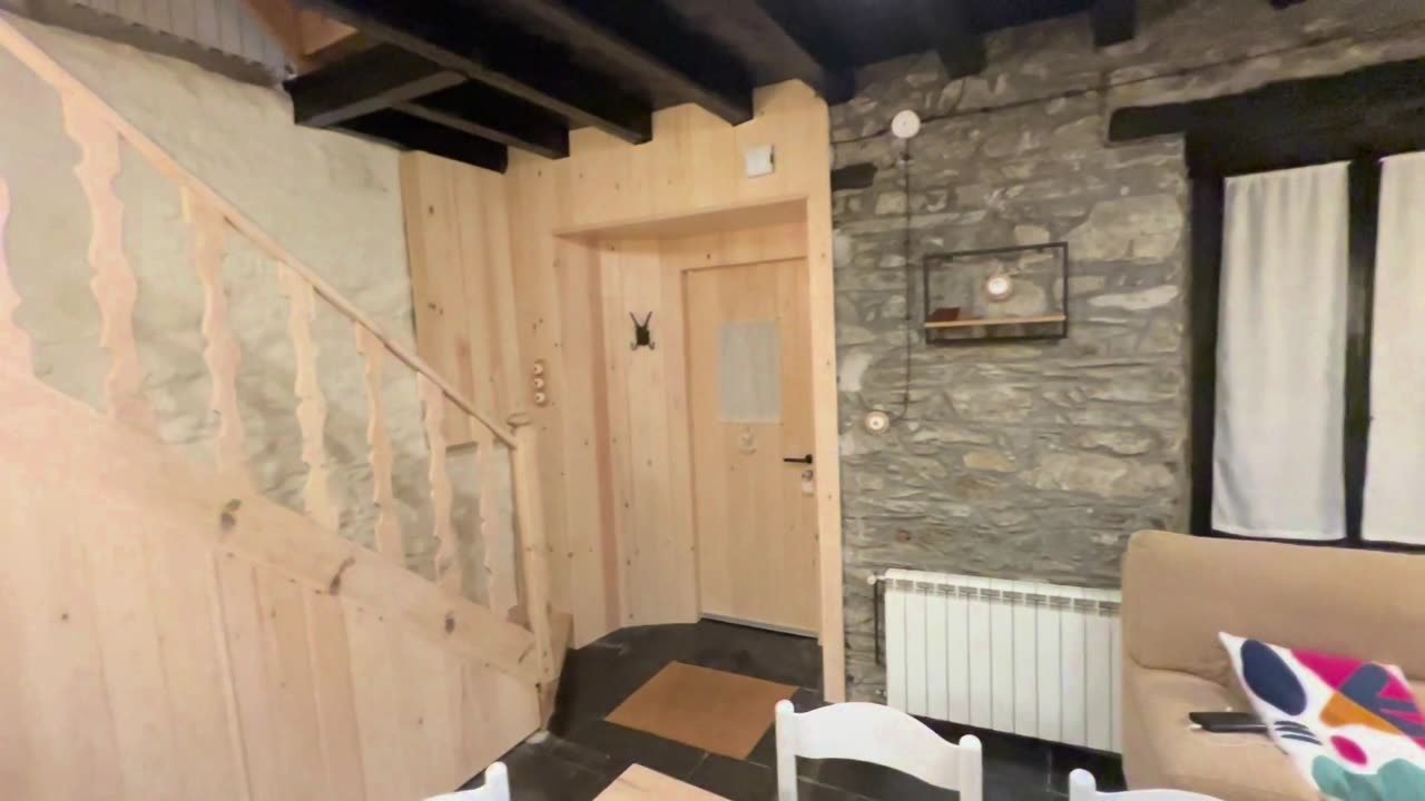 Entrada con escalera de madera y muros de piedra